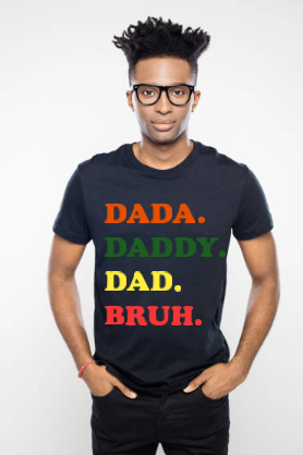 A person wearing a black crew neck t-shirt with the text 'DADA. DADDY. DAD. BRUH.' printed in colorful letters on the front.