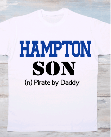 A white crew neck t-shirt with the text 'HAMIPTON SON' and 'Pirates by Daddy' printed in blue and black colors on a wooden background.