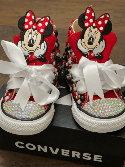 Red Converse sneakers with custom bling rhinestones and Minnie Mouse design on the tongue, displayed in a packaging with the brand name 'Converse' visible.